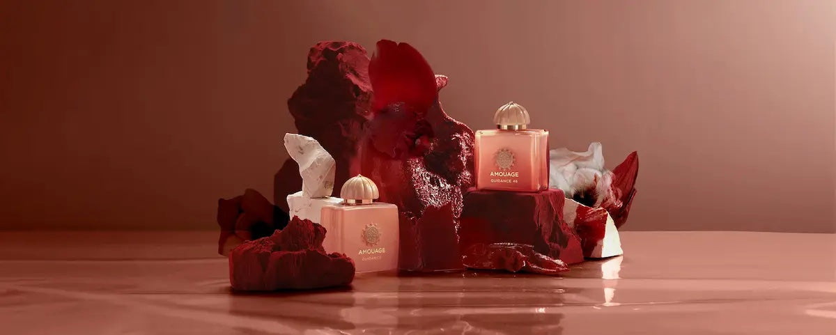 Two amouage guidance 46 bottles with red floral arrangements on a wooden surface.