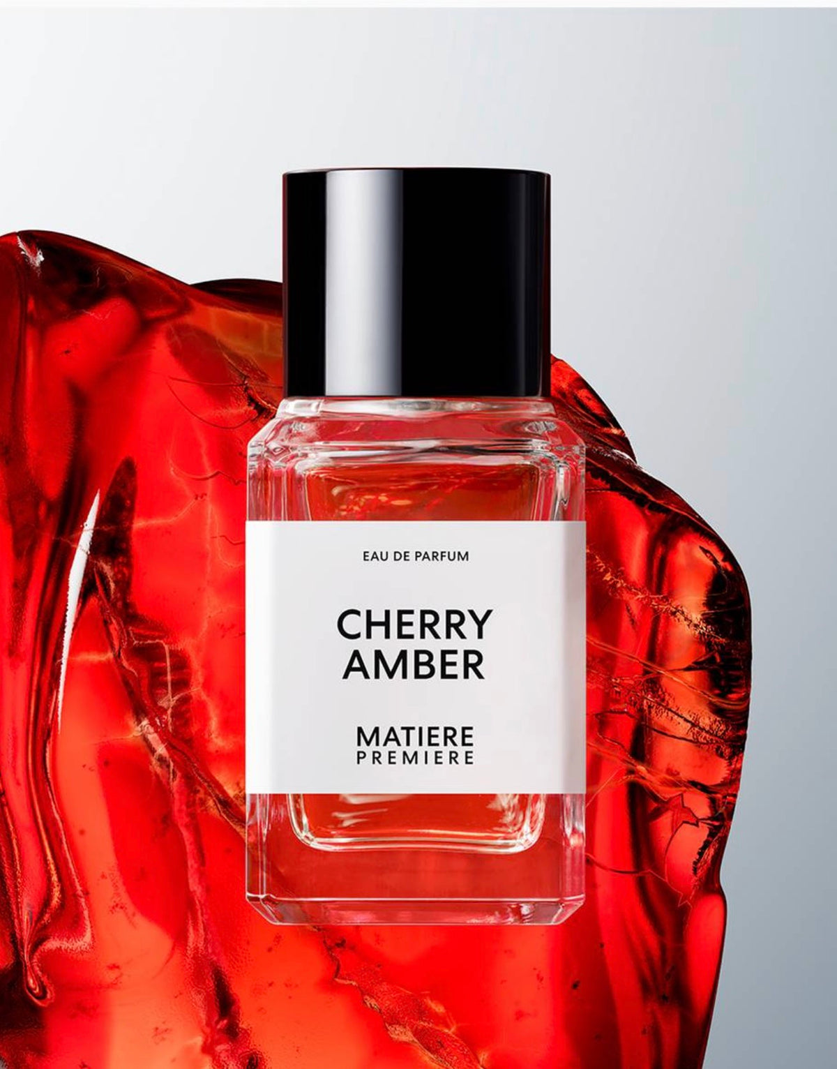 A perfume bottle called Matiere Premiere cherry amber a clear glass bottle with a white logo and black text